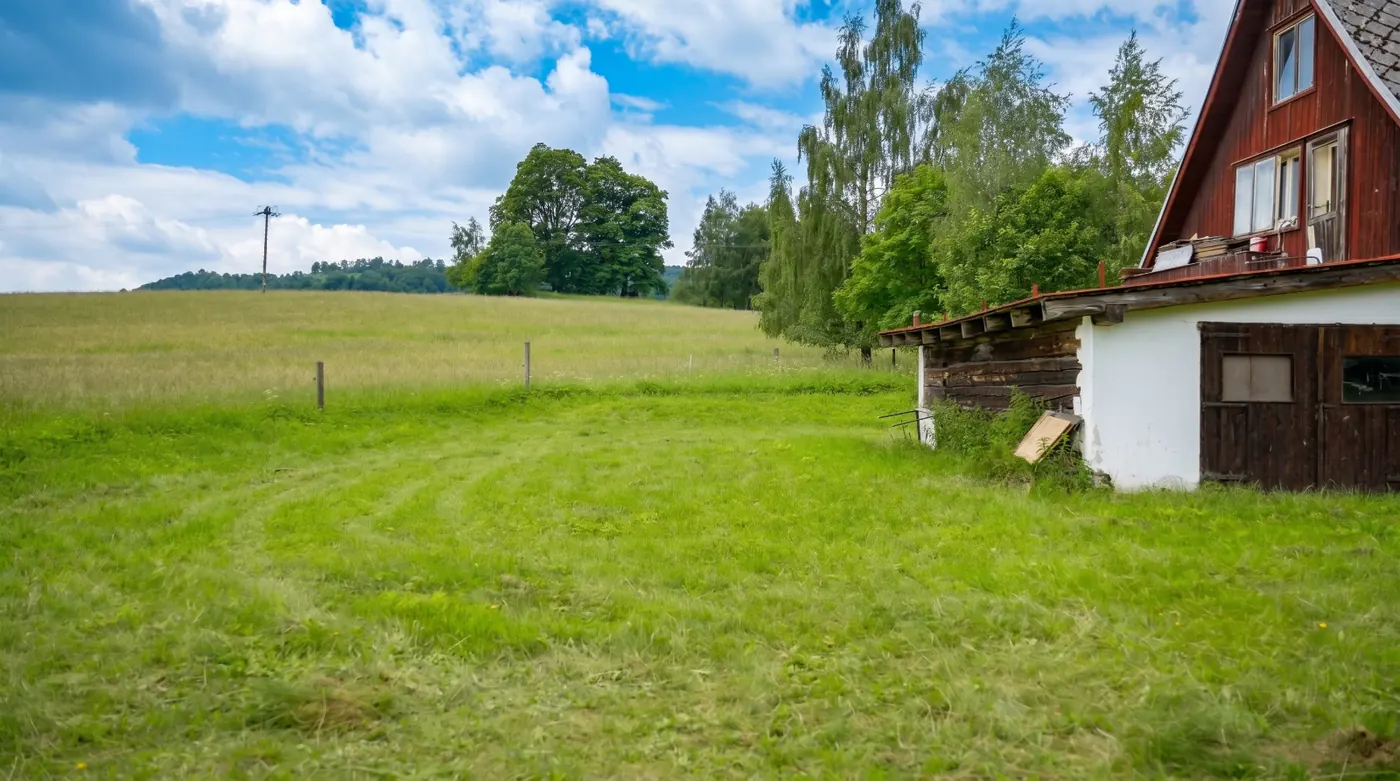 Pozemek se stavením a svahy v pozadí